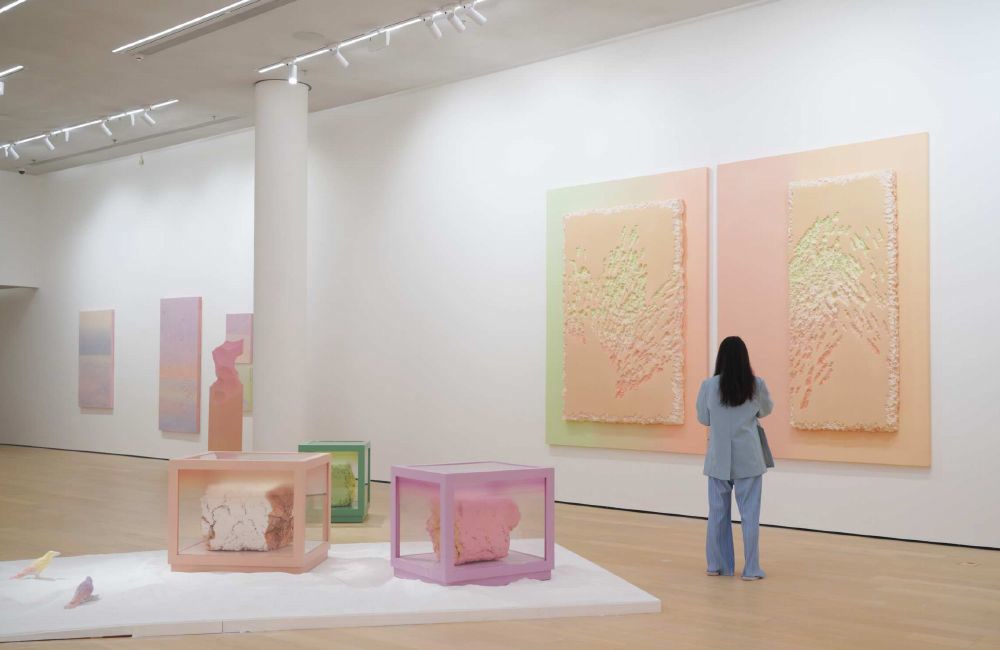叶帆作品展览现场，观众站在大型粉色双联作品前，前景陈列着树脂装置。